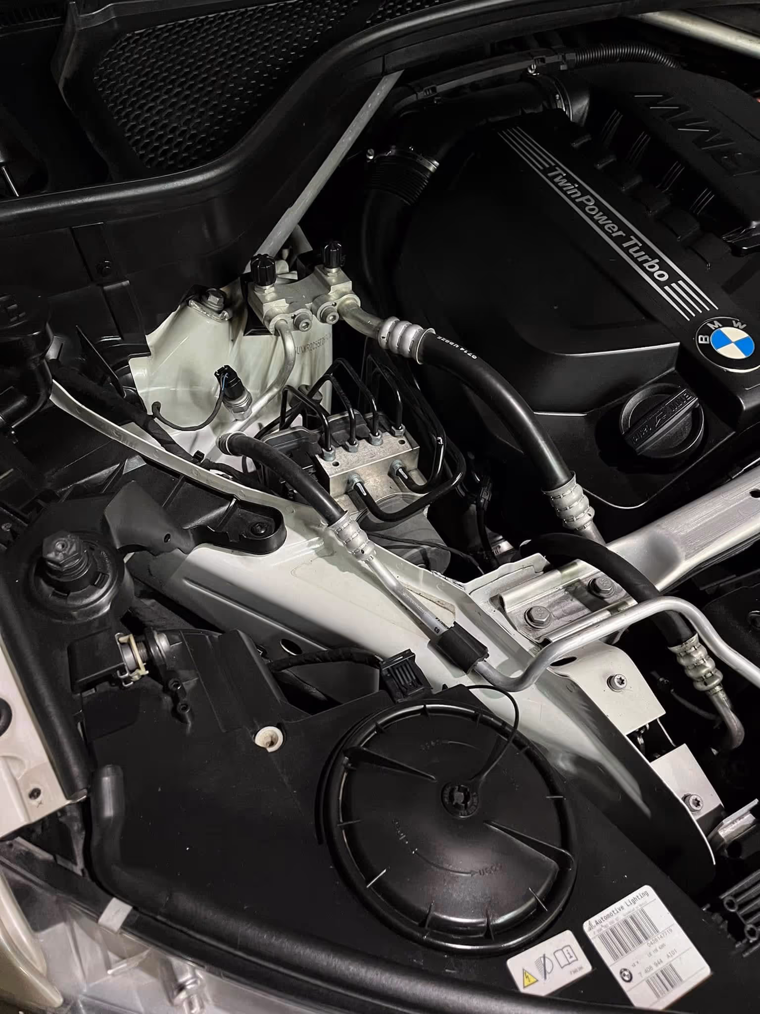 Close-up of a BMW TwinPower Turbo engine compartment with visible pipes and engine cover.