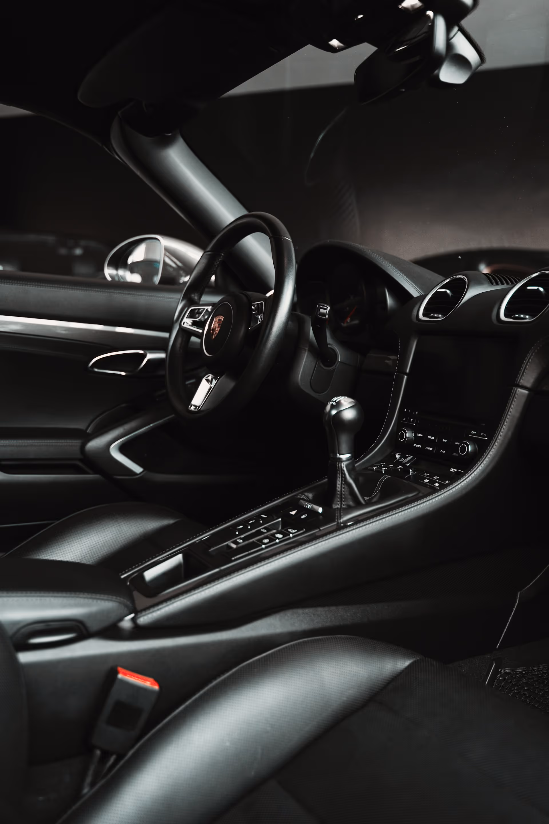 Interior of a luxury sports car showing the steering wheel, manual gear shift, and dashboard controls.